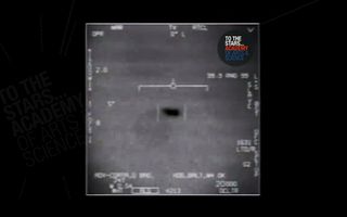 a grainy black and white video taken by the navy that shows two dark splotches that are thought to be ufos