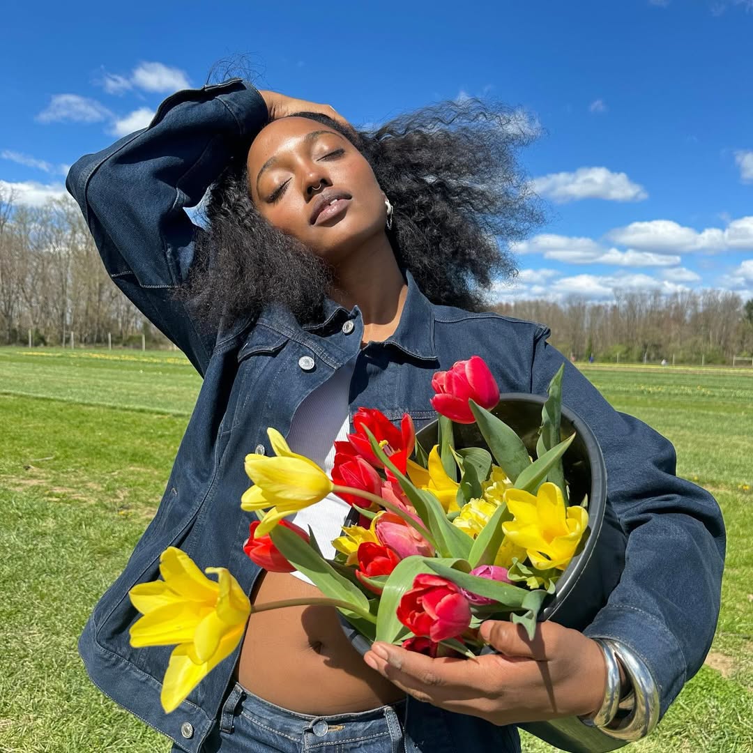 An image of content creator Gabrielle Richardson wearing a denim jacket and holding a bouquet of tulips.
