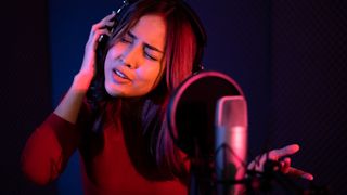 Lady singing into a microphone in the studio