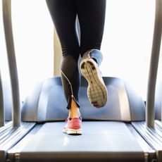 Woman wearing sneakers and tights running on treadmill