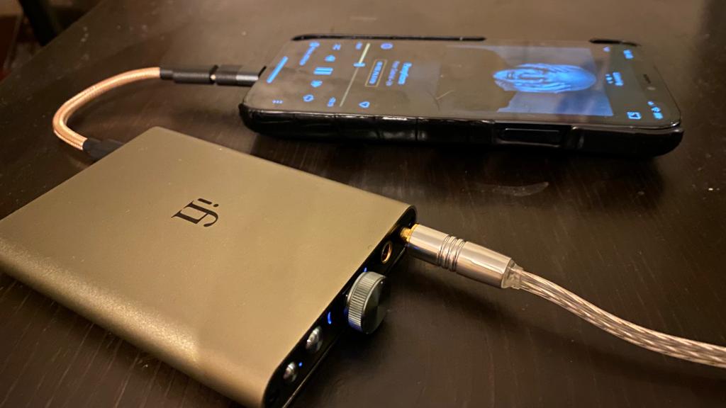 iFi hip-dac 3 on a black table, next to a smartphone
