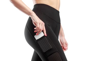 Profile image of a female feet dressed in a black leggings, put the phone in her pocket, white background, best leggings with pockets