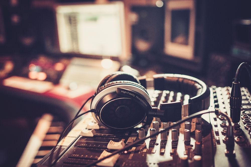 A pair of headphones resting on an audio mixer in a studio