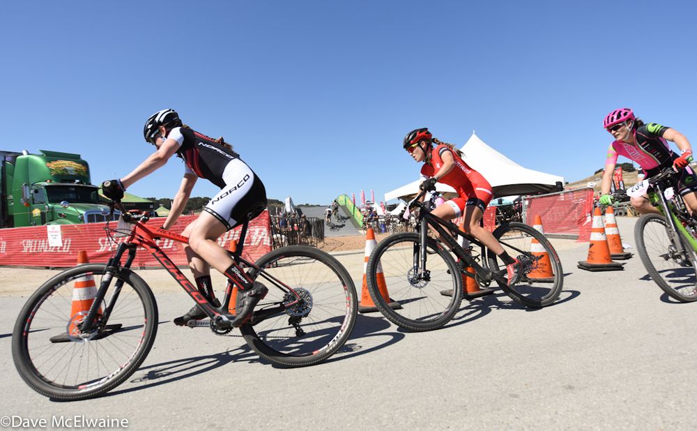 A Norco rider leading Kate Courtney and Mical Dyck around a tight corner