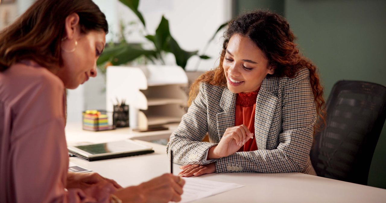 A female lawyer helps a woman with her estate plan at a desk.