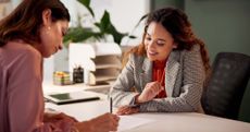 A female lawyer helps a woman with her estate plan at a desk.