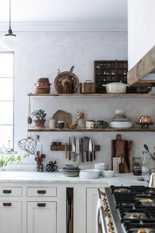 Rustic white kitchen with open shelving used as pan storage