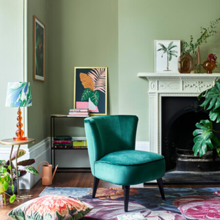 a green painted living room with dark green velvet chair and floral rug