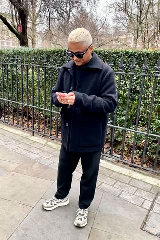 Sunil Makan, editor, is seen wearing an all black outfit, wool coat, trousers and Salomon trainers during London fashion week aw23