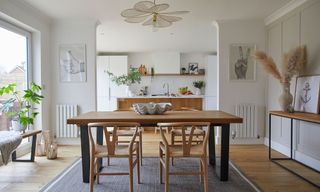 white kitchen diner with industrial table wishbone chairs grey rug pendant light kitchen island granite worktop