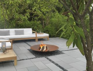 corten steel fire pit in the centre of a paved patio