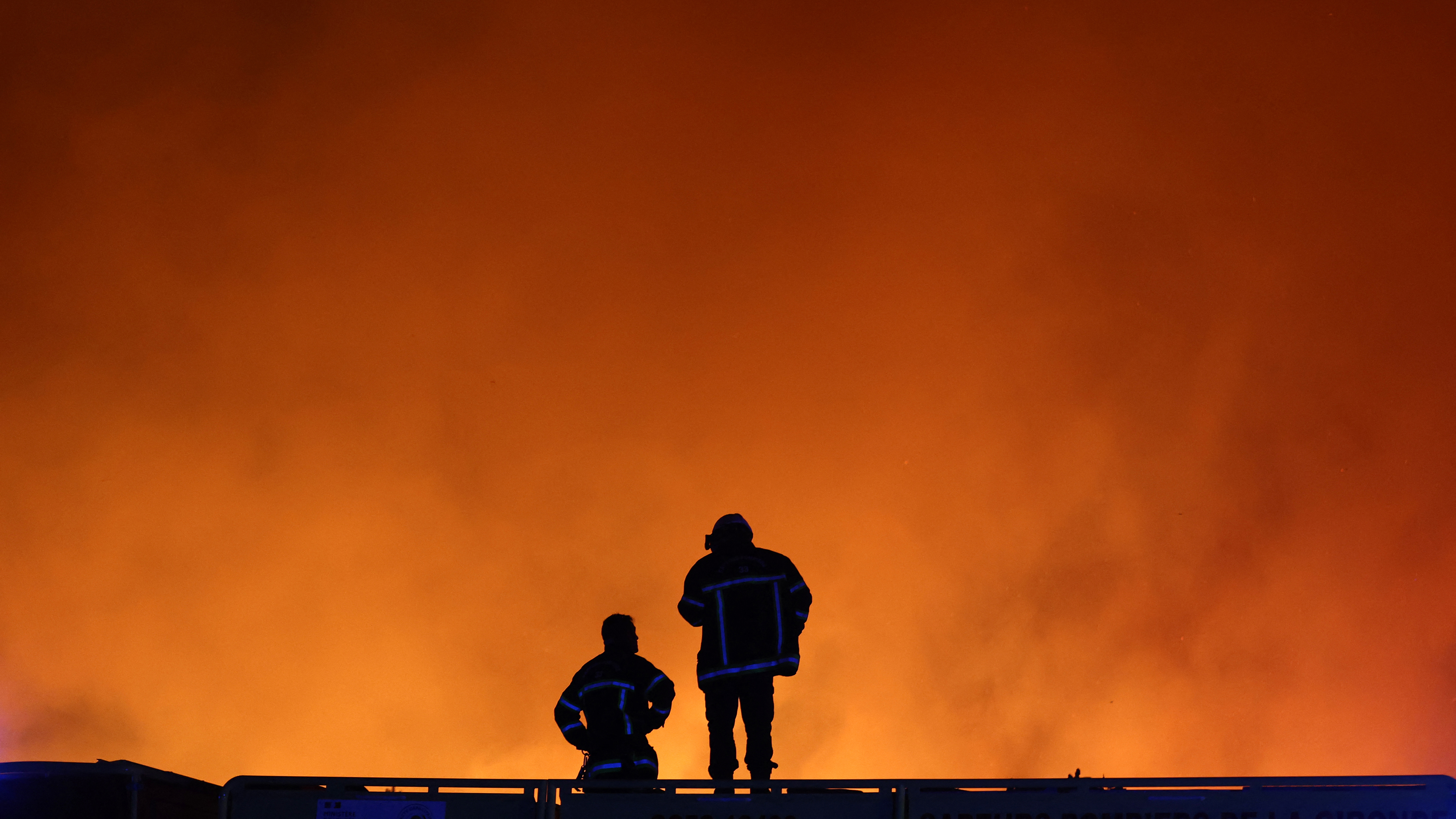 TOPSHOT - Firefighters monitor a wildfire in Le Porge, south-western France on July 22, 2026. A fast-moving wildfire has burned 900 hectares north of Arcachon Bay in southwestern France, forcing the evacuation of more than 4,000 residents and tourists. The blaze, described by firefighters as exceptionally intense, spread sixfold in less than three hours through dense pine forests and is now advancing toward Ares and Lege-Cap-Ferret. The area was previously devastated by major wildfires in 2022. (Photo by ROMAIN PERROCHEAU / AFP via Getty Images)