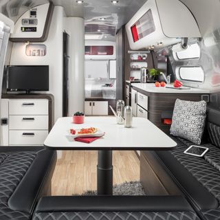 airstream model with aluminium roof and white table with black seat
