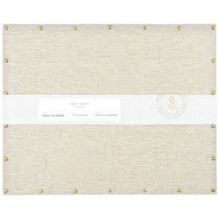 A cream fabric covered rectangular pin board. 