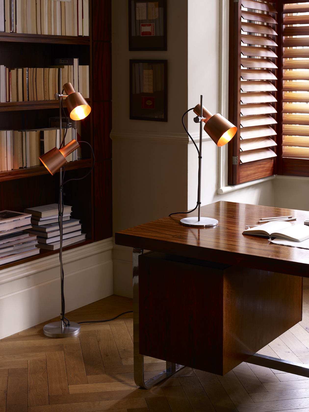 dark wood home office with red-wood shutters, wood floor and desk and a large bookcase