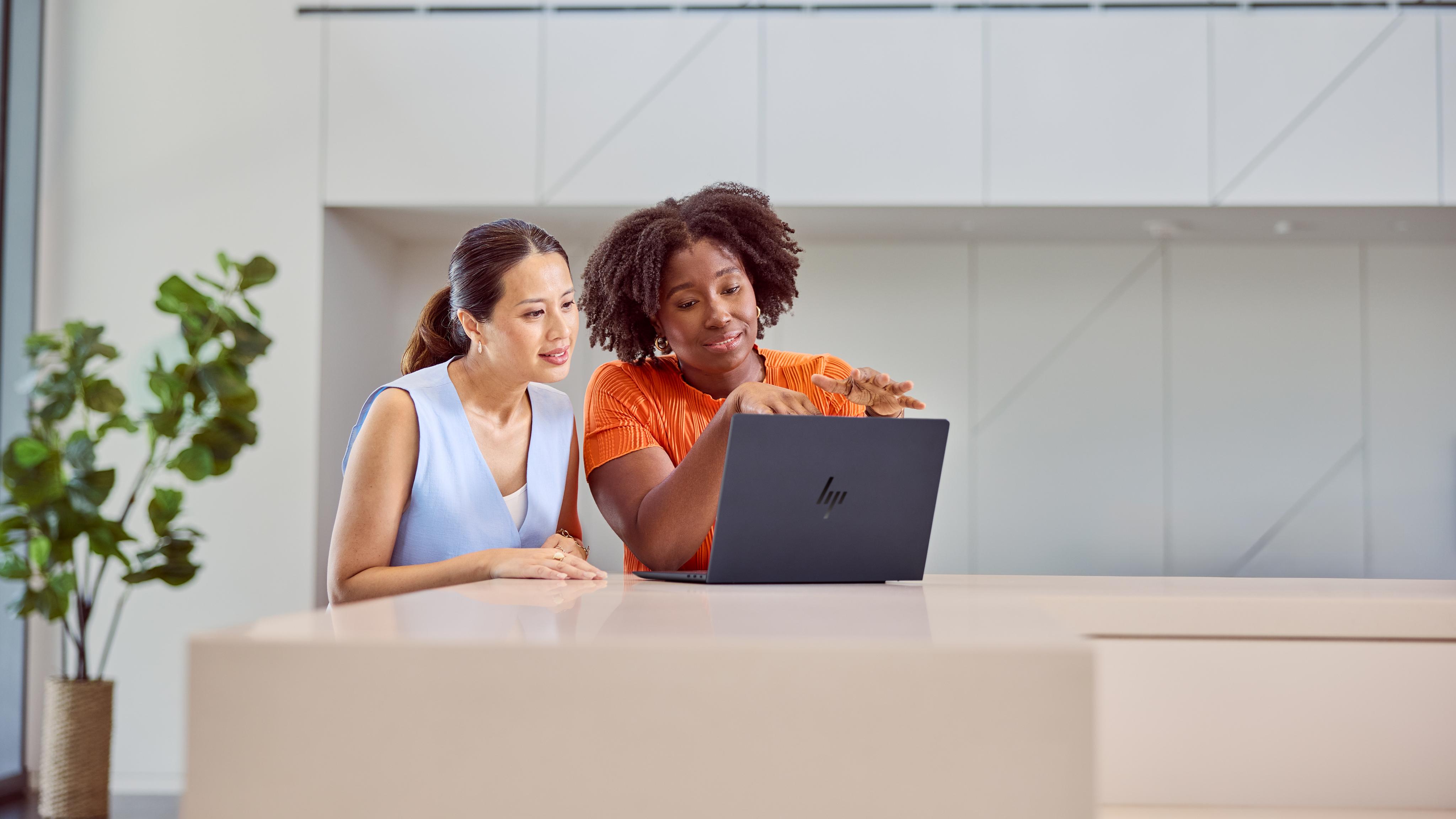 Two people seated at a table while using the HP EliteBook Ultra 14 (G1i) together.