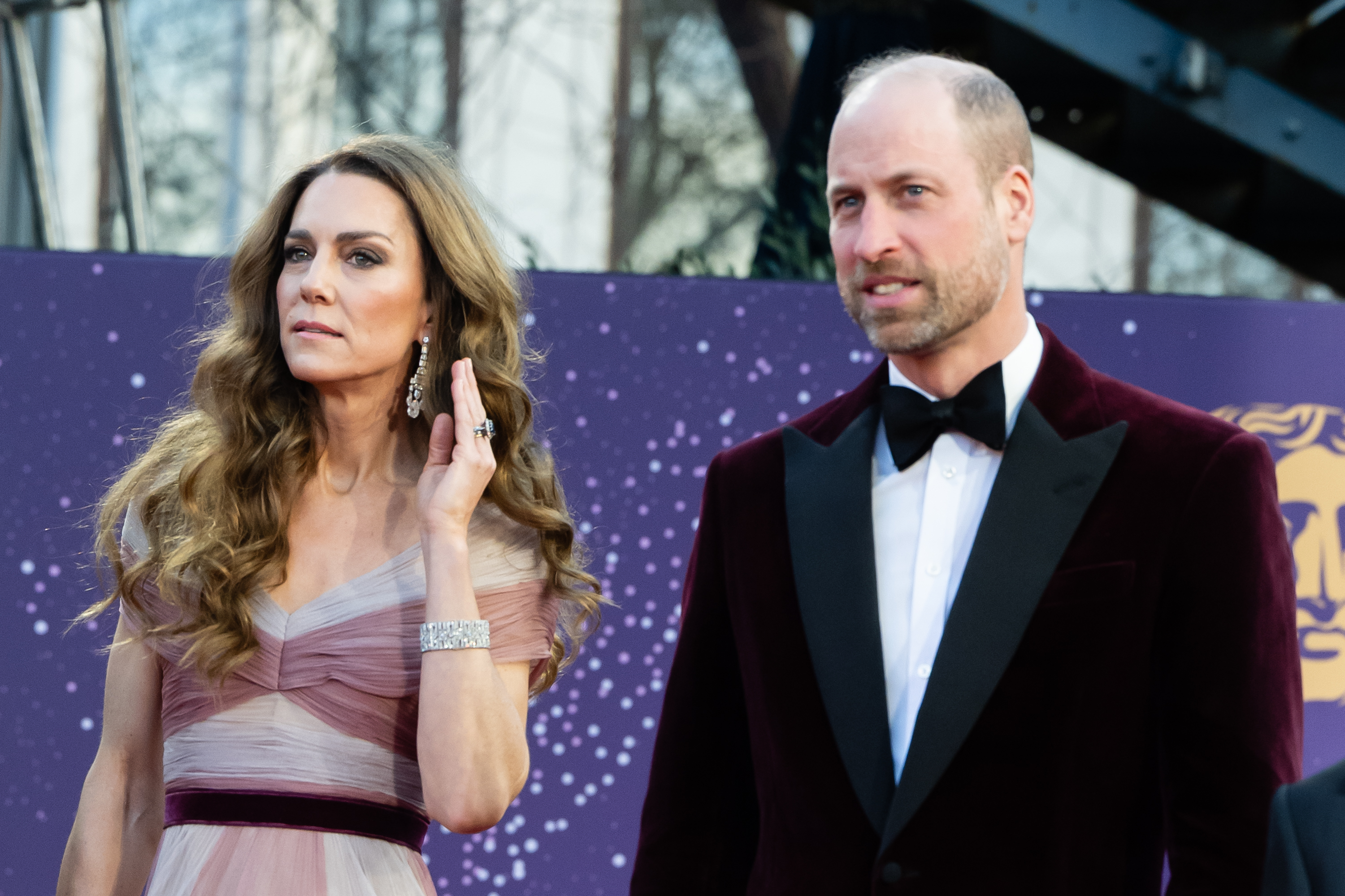 Princess Kate in a pink gown touching her hair walking the red carpet with Prince William at the 2026 BAFTAs.