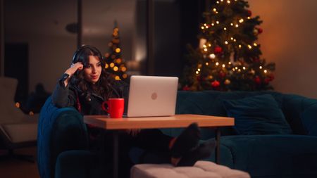 A young woman is relaxing at home and using her laptop in the living room during Christmas