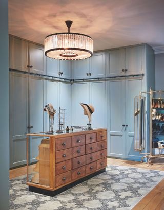 Blue walk in wardrobe with central storage and show rack