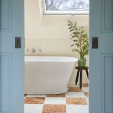 ensuite bathroom behind pocket doors with white bath and red and white checkerboard tiles