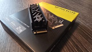 Corsair MP700 Elite SSD with its packaging on a desk.