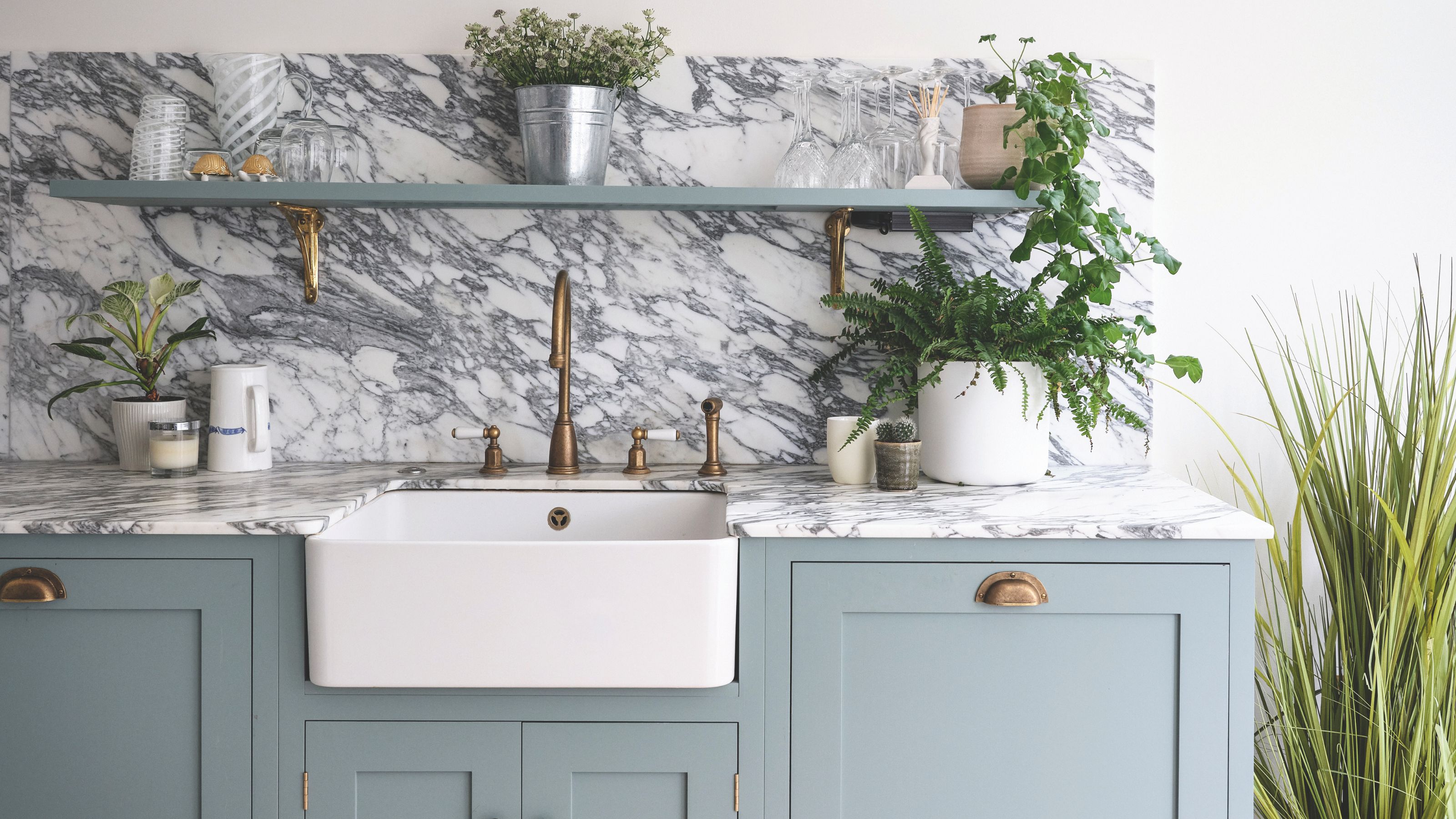 Marble kitchen worktop and sink area with a white ceramic sink and blue cabinets underneath it