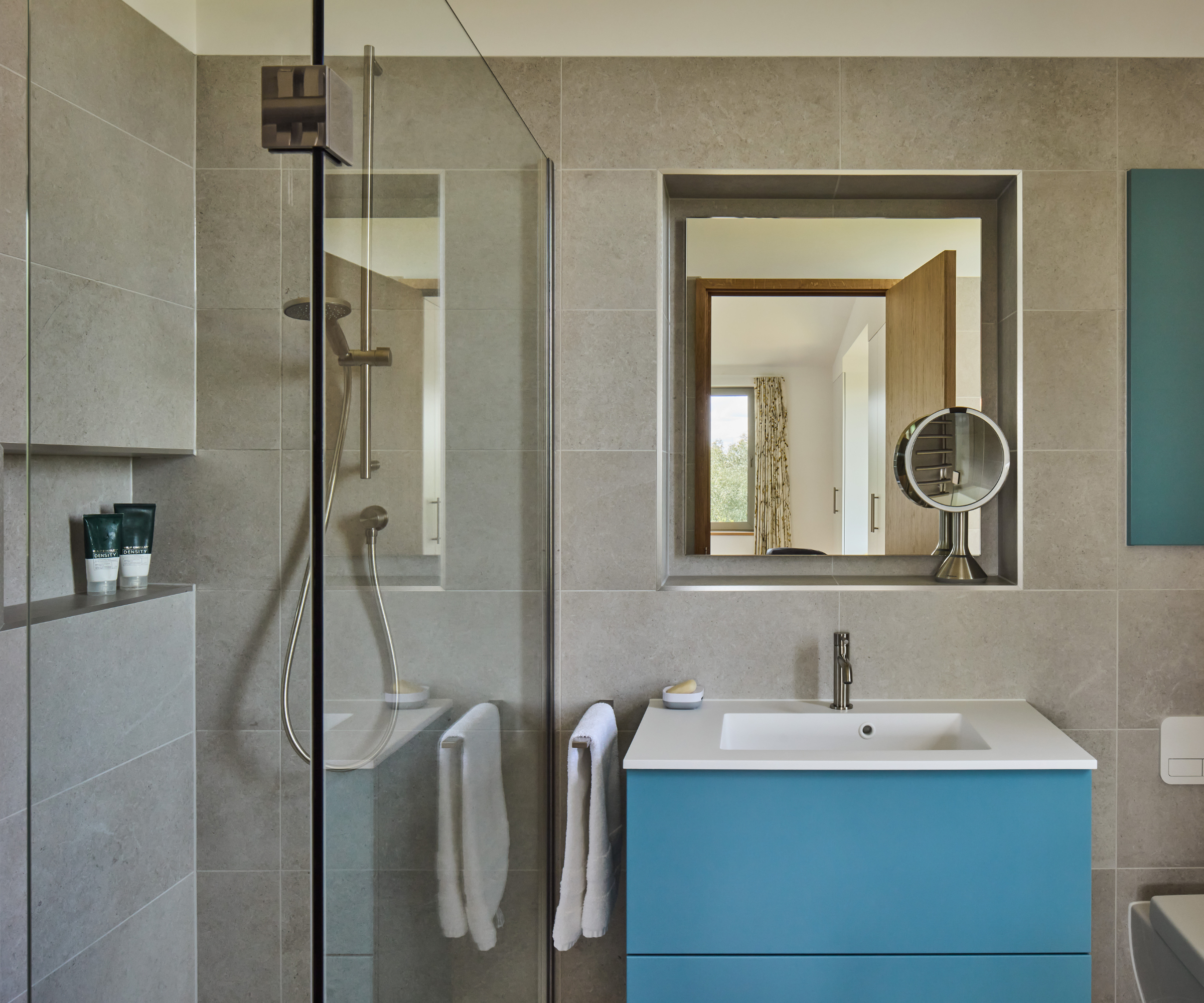 Bathroom with stone tiles and blue under sink cabinet 