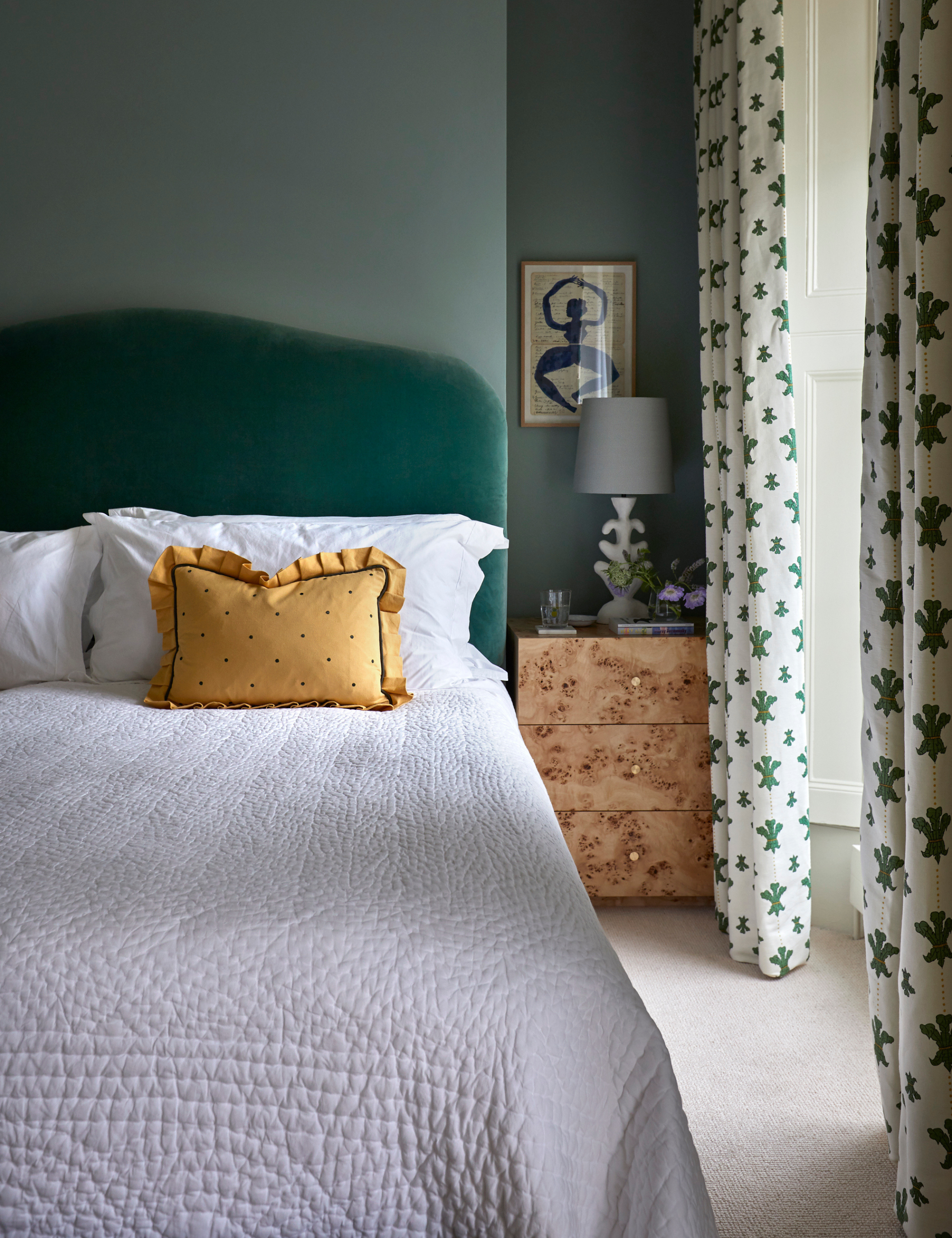 Bedscape styled with a white textured quilt and yellow ruffle bordered pillow sham