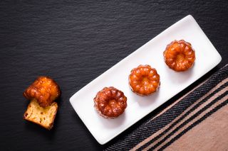 French pastry Canele rum and vanilla flavor thick caramelized crust on black slate plate