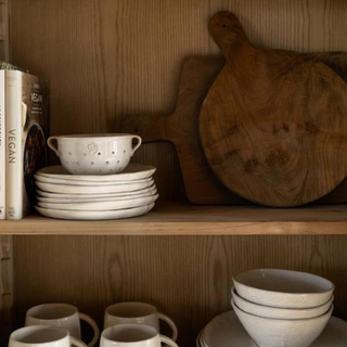 Wooden shelves with white dishes and bread boards.
