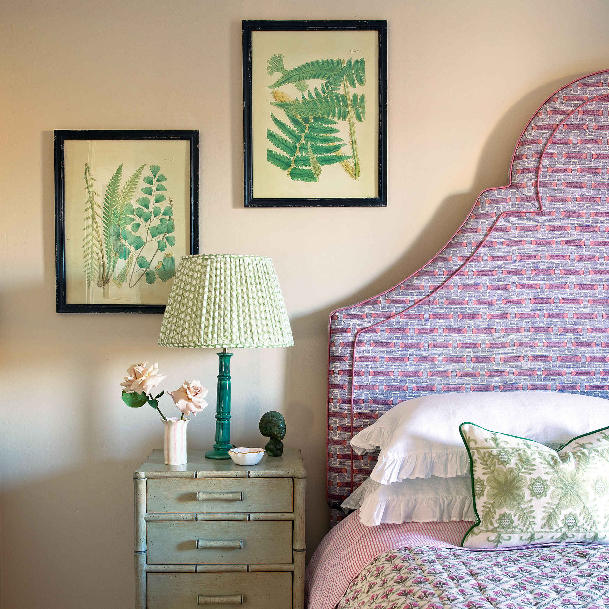 Pink headboard with blush wall and botanical prints and a bamboo effect side table