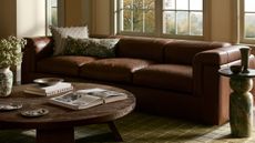 Fall pillow covers by Joon Loloi pictured in a moody living room featuring a leather sofa and wooden coffee table