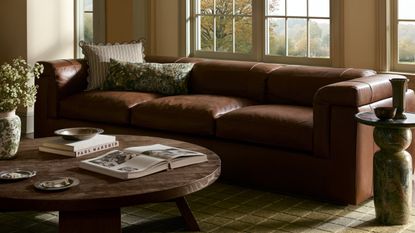 Fall pillow covers by Joon Loloi pictured in a moody living room featuring a leather sofa and wooden coffee table