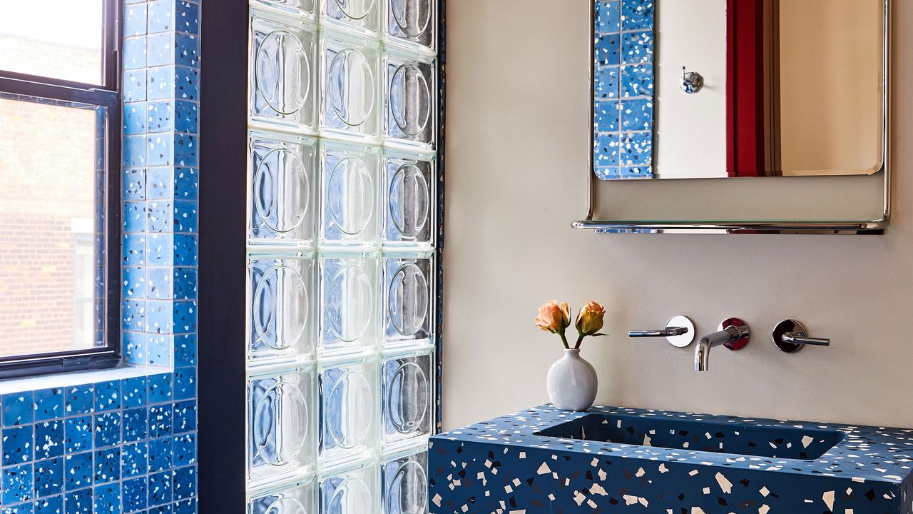 a blue terrazzo sink and glass blocks in a bathroom