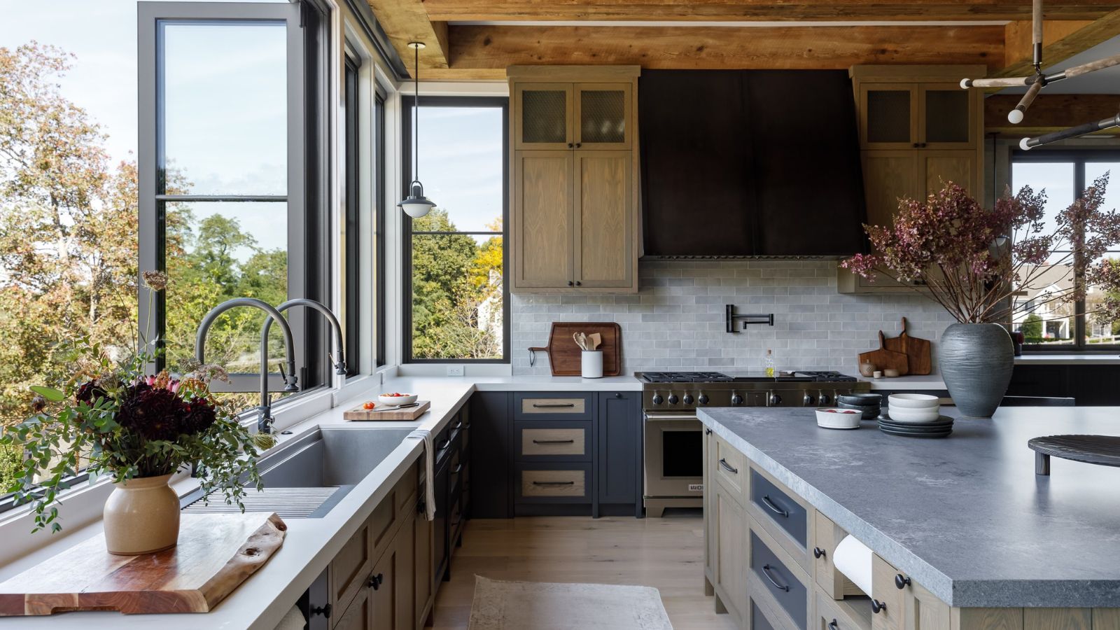 Large kitchen with bi-fold windows and island. It&#039;s bright, open and has triple aspect windows showing the home&#039;s elevation with trees all around