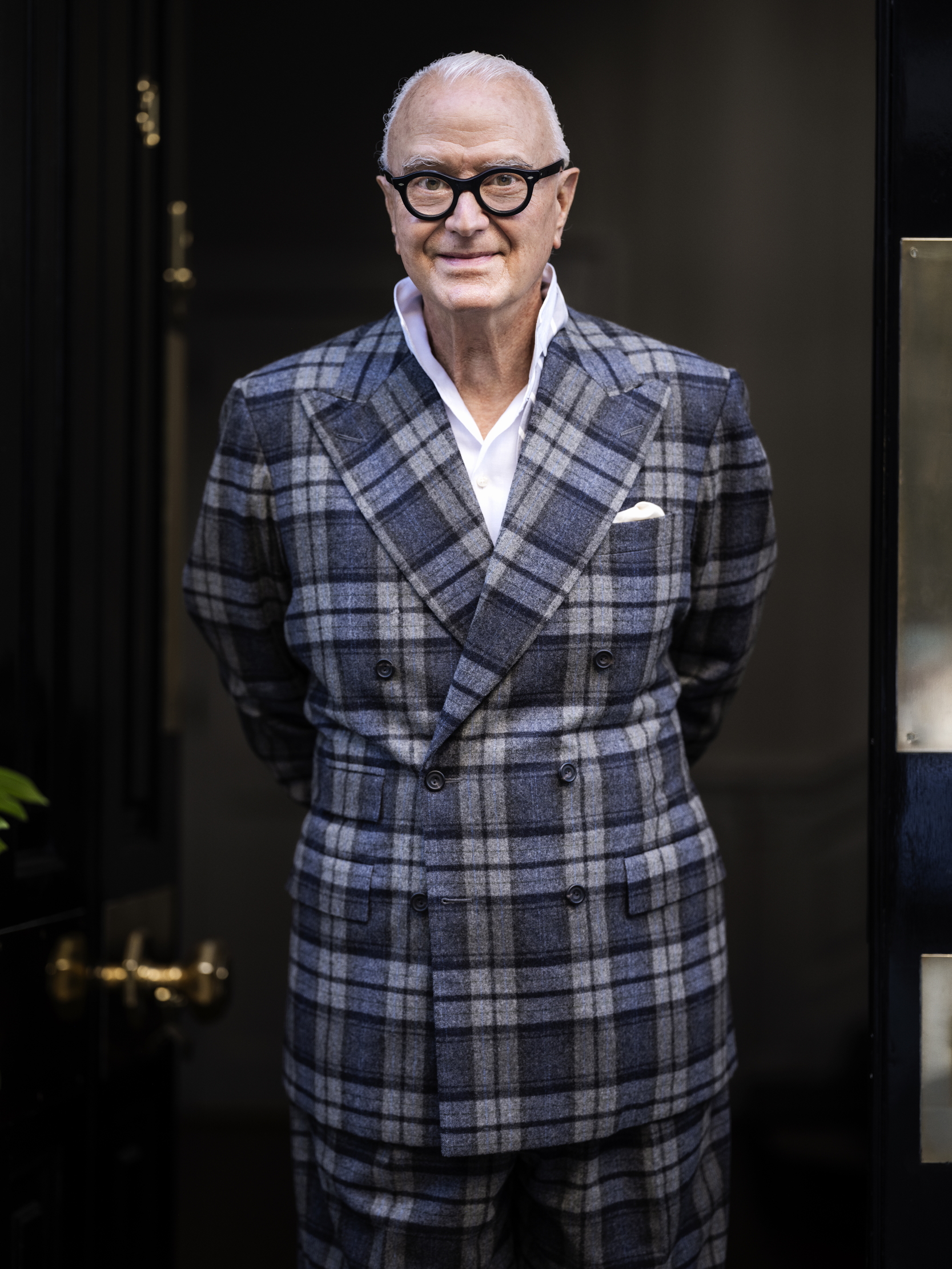 The designer Manolo Blahnik, wearing his signature thick rim glasses and a delightful double-breasted blue-check suit