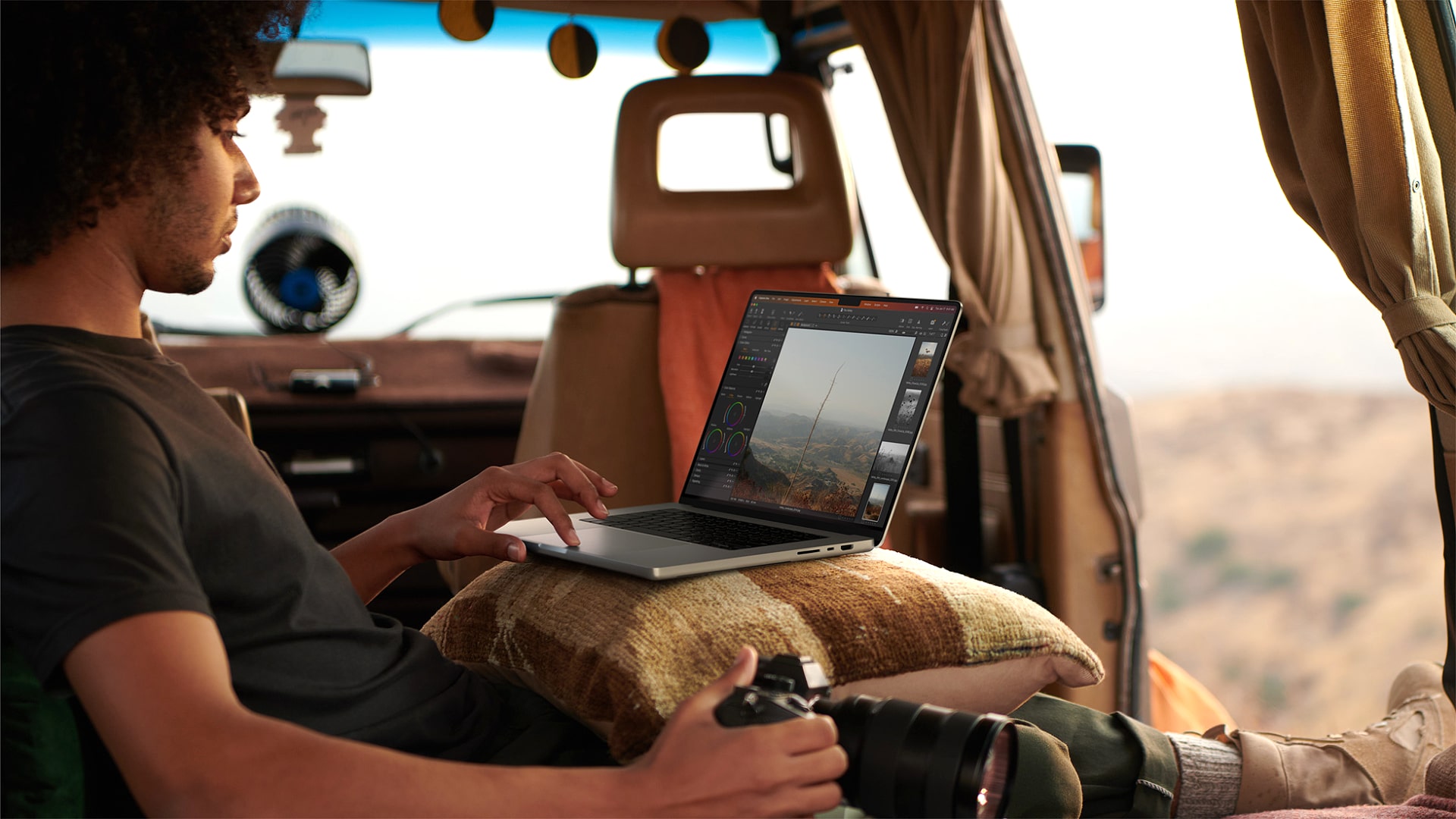 A photographer using a MacBook Pro in the field.