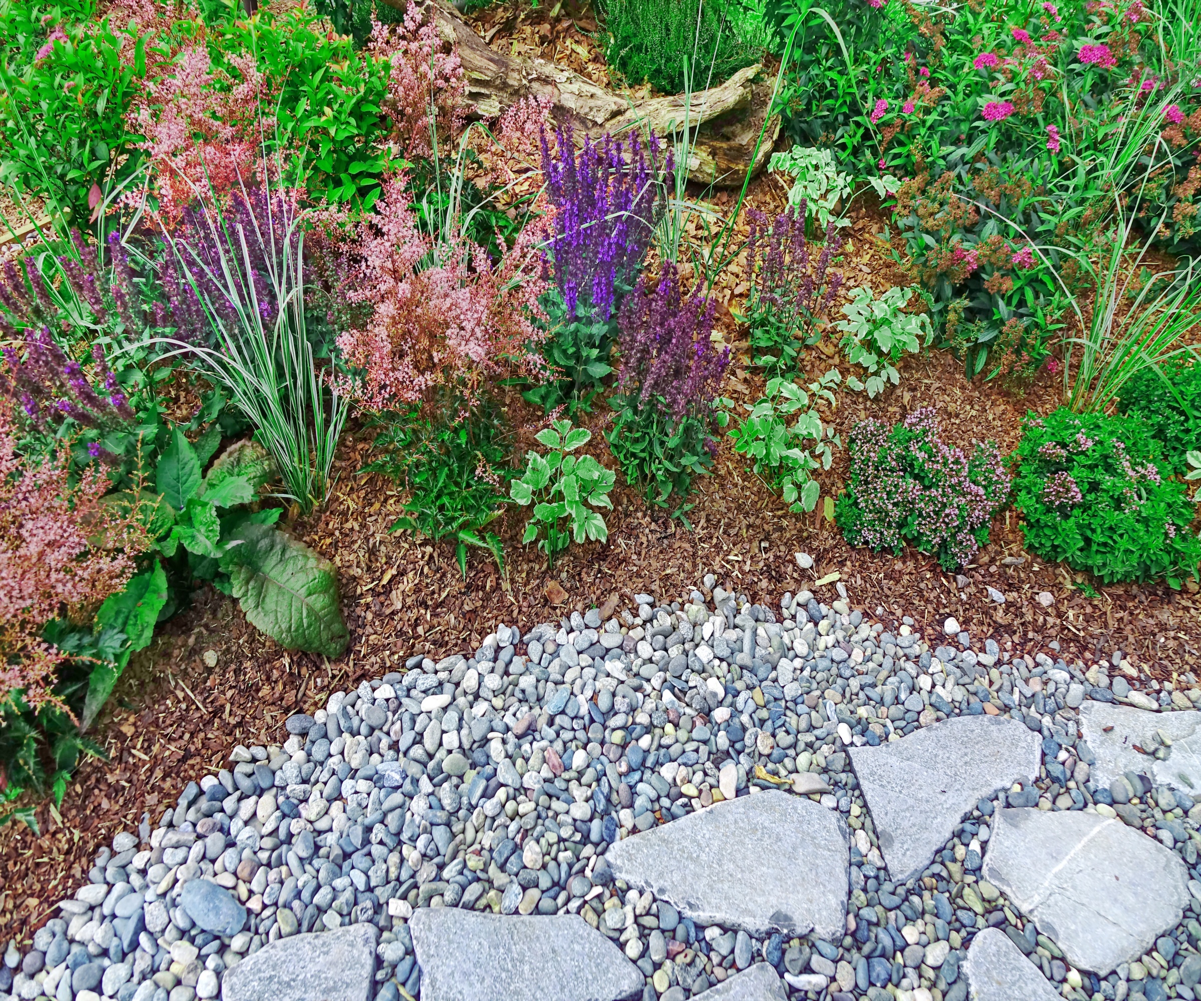 Neat garden with border mulched with bark chips next to a gravel and stone path