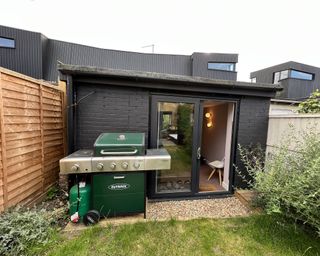 A garden outbuilding home ofice with sliding doors and green barbecue setup
