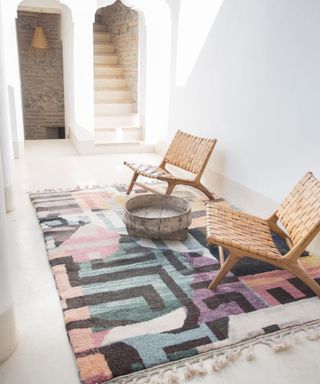 Bright boho pattern textured rug with tassel fringing, and woven chairs.