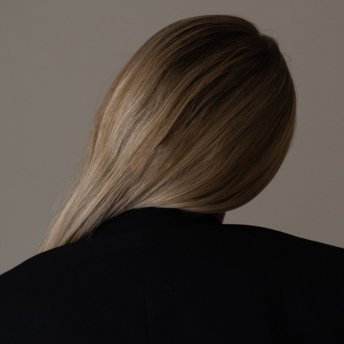 An image of a woman in a black coat with her blonde hair swept over her shoulder.