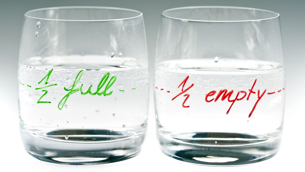 A glass that&#039;s marked half empty sits next to a glass marked half full.