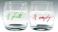 A glass that's marked half empty sits next to a glass marked half full.