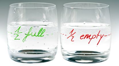 A glass that's marked half empty sits next to a glass marked half full.