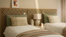 Twin bedroom with patterned headboard, sage pillows, and white bedding with neutral walls.