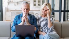 An older couple stare at a laptop worried about their Medicare benefits.