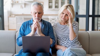 An older couple stare at a laptop worried about their Medicare benefits.