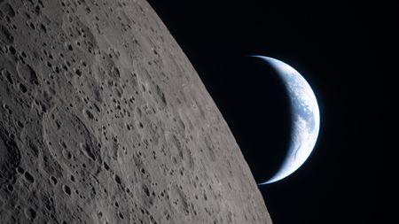 A view of Earth from the moon, with half the Earth illuminated and the gray surface of the moon in the foreground.