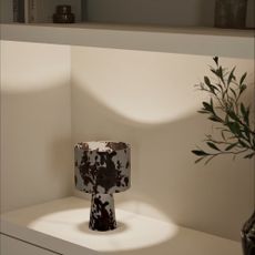 Switched on M&S Fabric Cow Print Table Lamp on a shelf next to a vase of foliage