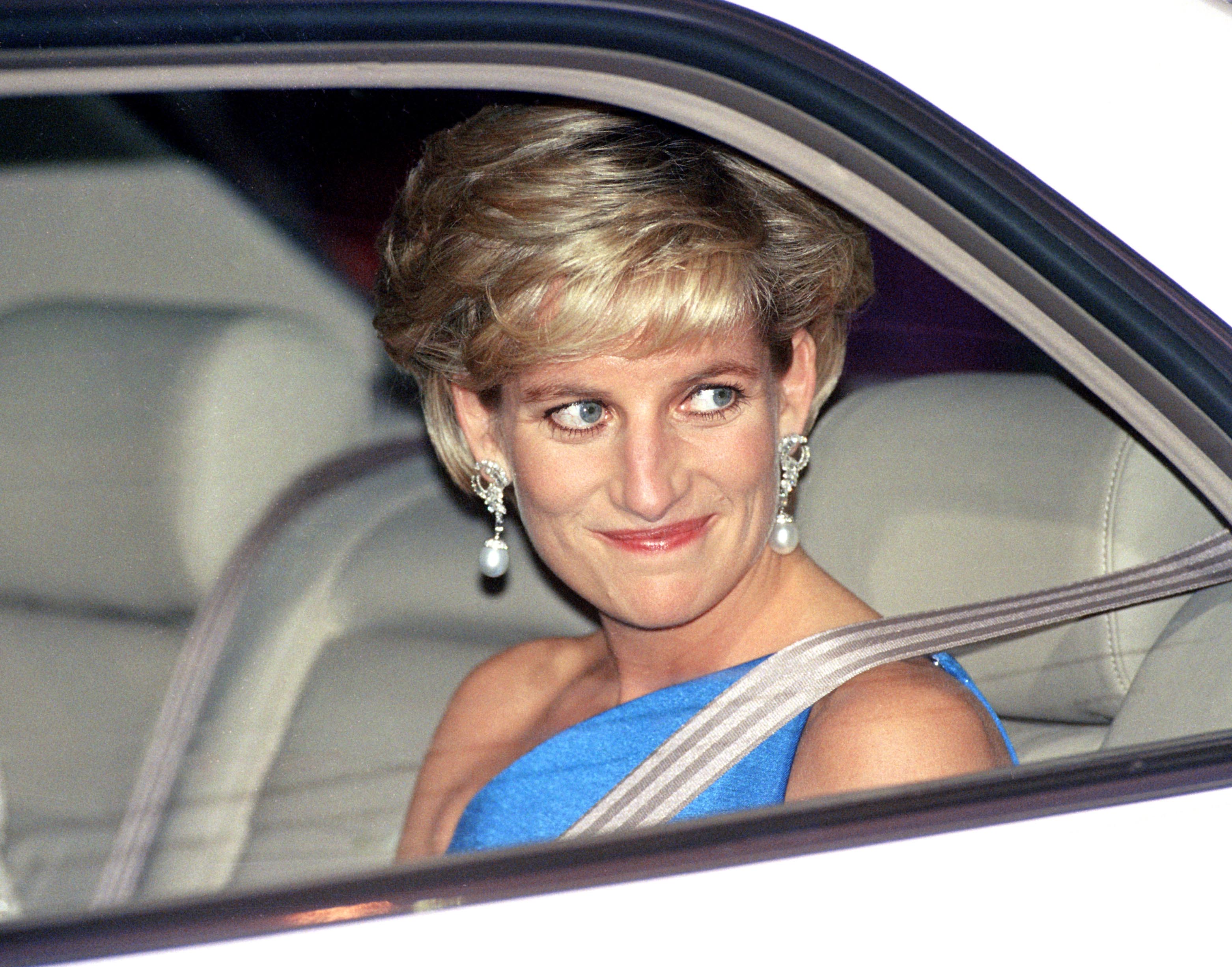 Princess Diana wearing a blue gown looking out a car window